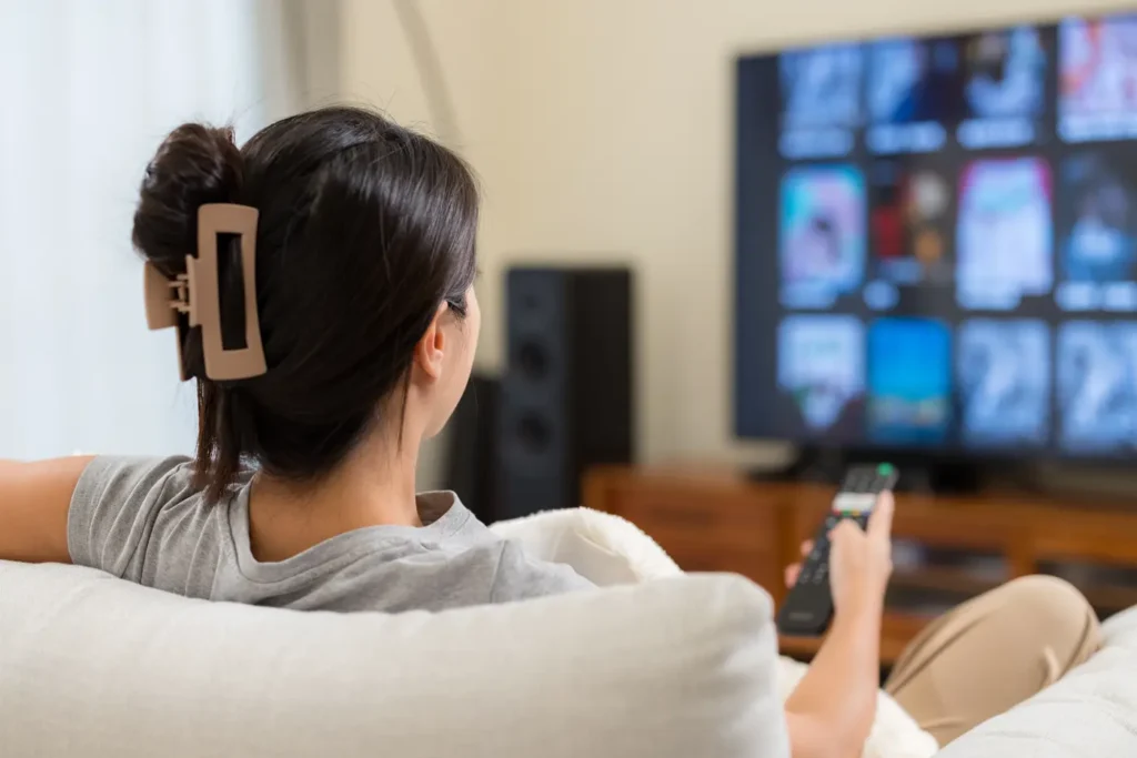 Femme regardant la télévision à la maison avec iptv smarters, profitant d’un abonnement IPTV fiable en France — meilleur service IPTV pour films et séries en HD et 4K.